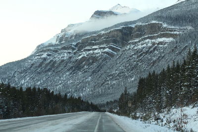 Road amidst snowcapped mountains against sky during winter