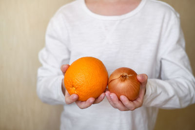 Close-up of man holding orange fruit