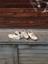 Old forgotten white sneakers on a wooden wall background