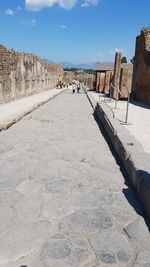 Footpath leading to built structure against sky