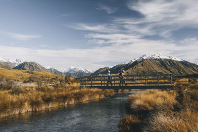 Couple of young hikers crossing a creek, lake clearwater, new zealand