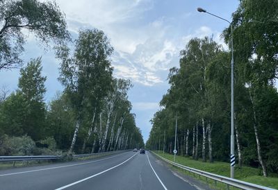 Road amidst trees against sky