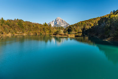 Scenic view of lake and mountains against clear blue sky