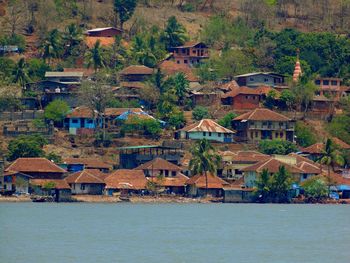 Houses by sea against buildings in city