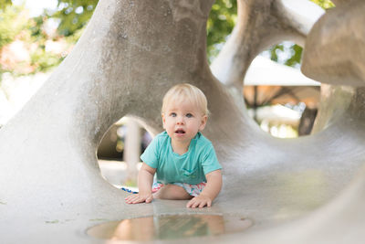 Portrait of cute baby boy standing on tree trunk