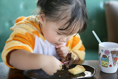 Cute baby girl eating the bread on table