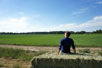 Rear view of man standing on field against sky