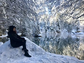 Side view of woman sitting on snow covered landscape