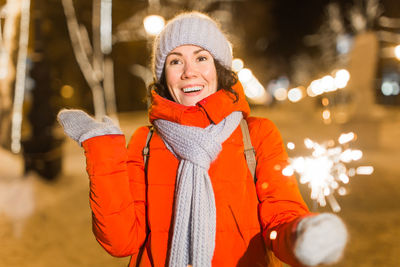 Young woman holding sparkler outdoors