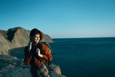 Woman standing by sea against clear sky