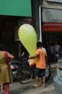 Rear view of people standing on street in city