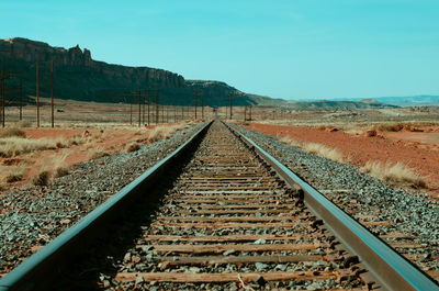 Railroad tracks leading towards mountain against sky