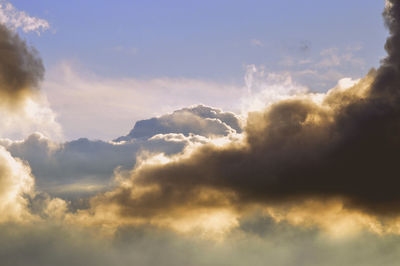 Low angle view of sunlight streaming through clouds