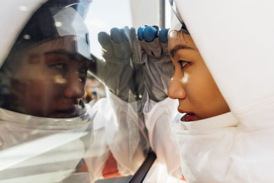 Female astronaut peeking through glass window