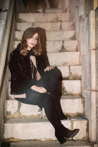 Full length of young woman sitting on staircase