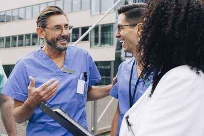 Happy male physician gesturing while talking with hospital staff