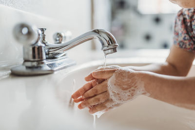 Close up view of young child washing hands with soap in sink