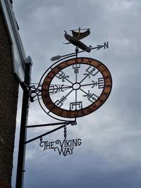 Low angle view of clock against sky