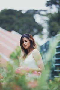 Young woman standing against plants