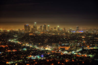 Illuminated cityscape against sky at night