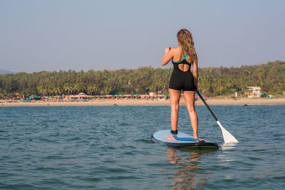 Woman standing in sea against clear sky