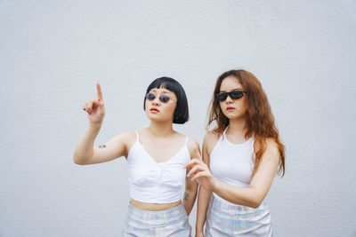 Lesbian couple gesturing while standing against wall outdoors