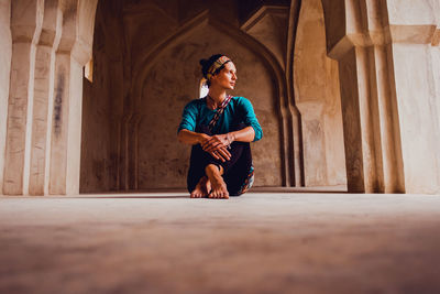 Full length of young woman standing against wall in building