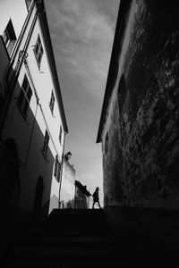 Low angle view of silhouette people standing by building against sky