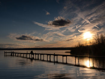 Silhouette swimming pool by sea against sky during sunset