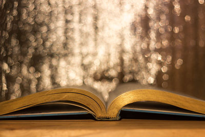 Close-up of open book on table against illuminated lights