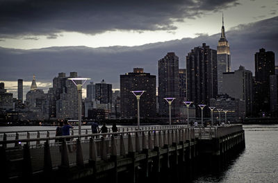 City at waterfront against cloudy sky