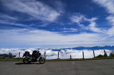 Cars parked on road against cloudy sky