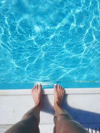 Low section of woman standing at poolside