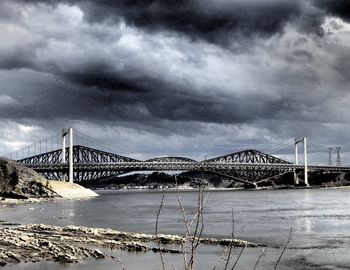 Bridge over sea against cloudy sky