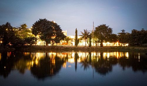 Reflection of silhouette trees in lake against sky