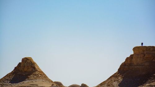 Low angle view of rock formations against clear blue sky