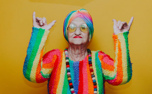 Portrait of senior woman gesturing against yellow background