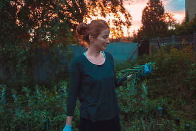 Woman holding plants standing outdoors