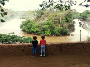 Full length rear view of men standing by trees