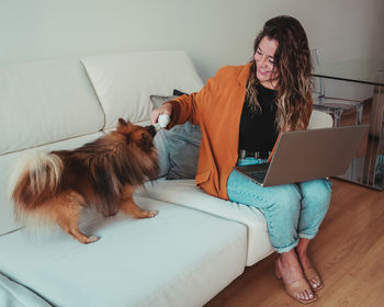 Young woman with dog on laptop at home