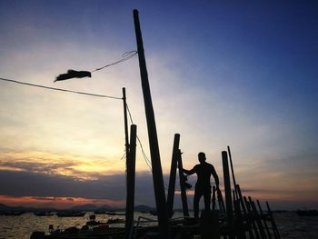 Silhouette people playing on beach against sky during sunset