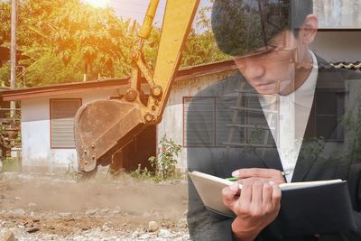 Double exposure image of businessman writing in diary and earth mover