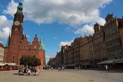 Low angle view of buildings amidst road against cloudy sky