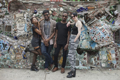 A group of friends posing in front of street art.