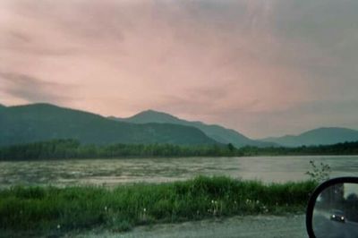 Scenic view of mountains against cloudy sky at sunset