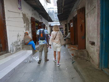 Rear view of people walking on footpath amidst buildings