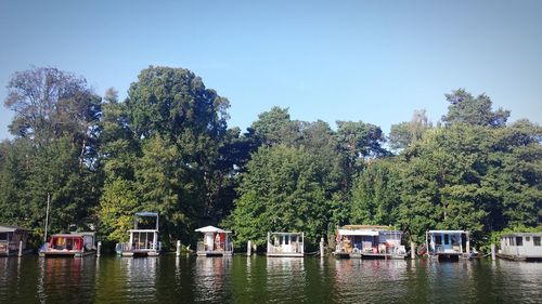 Boats moored in river with trees in background