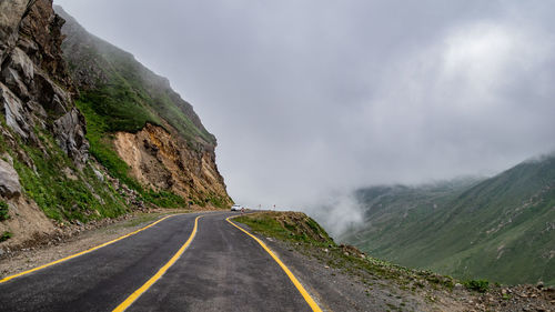 Road leading towards mountains against sky