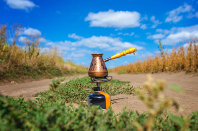 Copper cezve on a gas burner outdoors under blue sky. coffee in nature