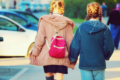 Rear view of girls holding hands while walking outdoors